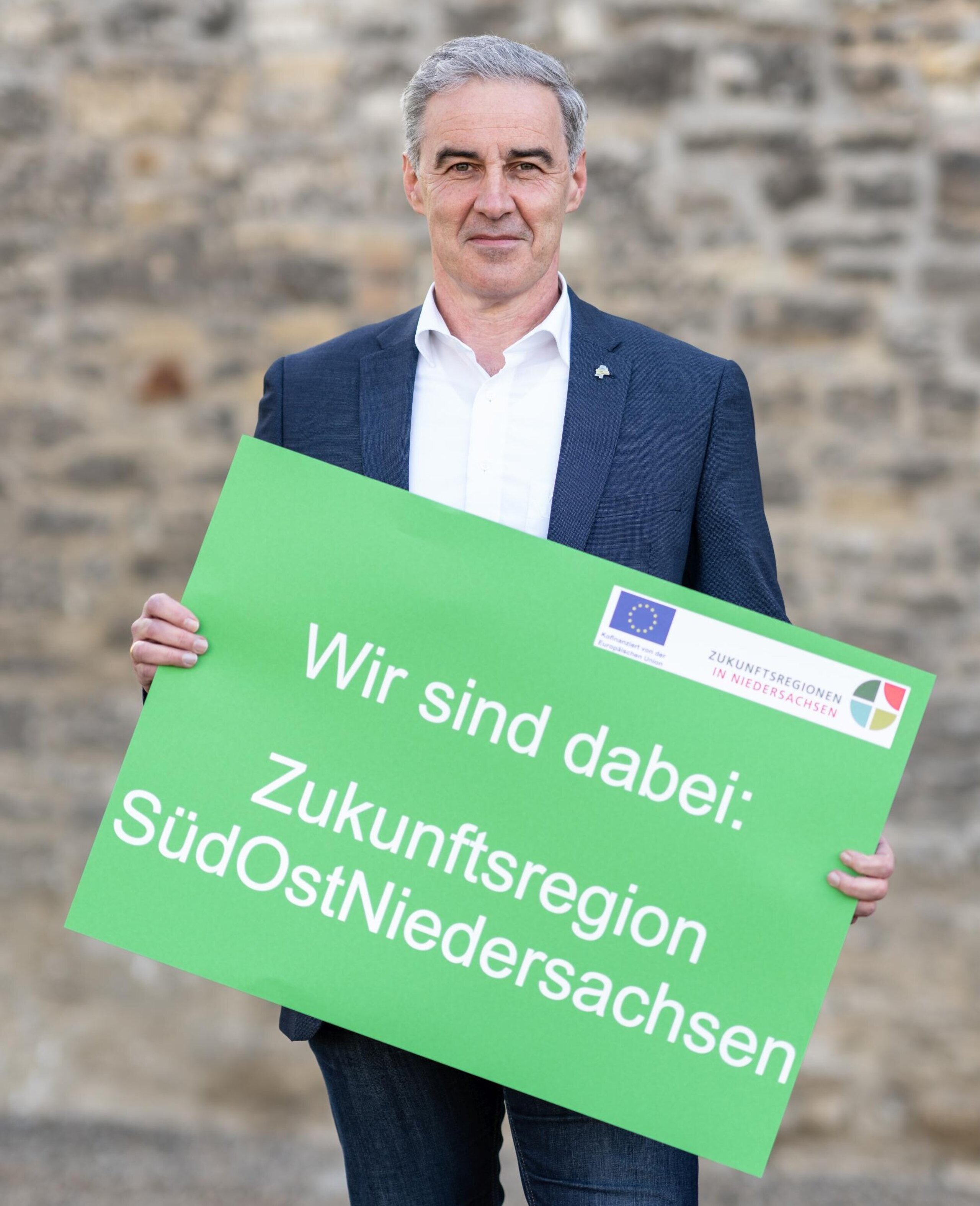 Ralf Sygusch hält das Schild "Wir sind dabei: Zukunftsregion SüdOstNiedersachsen"